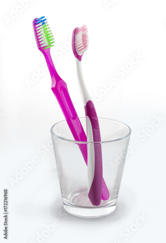 Two pink toothbrushes in a glass
