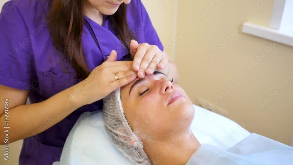 Cosmetologist Applying cream to the face and massages woman. Cosmetic procedures Mechanical cleaning of the face. Cosmetology. Cosmetologist Applying cream to the face and massages woman. Cosmetic procedures Mechanical cleaning of the face. Cosmetology.