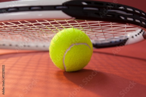 Close up of tennis racket leaning on ball