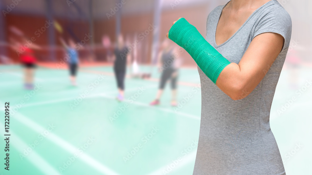 injury from sport, badminton player with green arm cast on blurred background woman players badminton