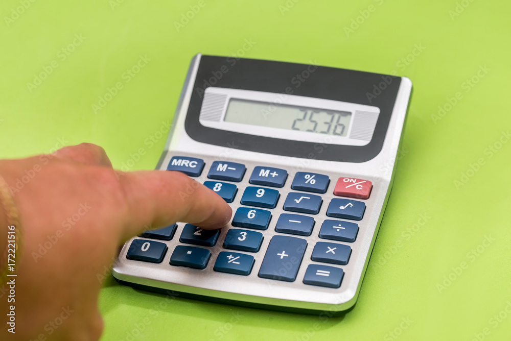 hand holding digital calculator isolated on green hand holding digital calculator isolated on green