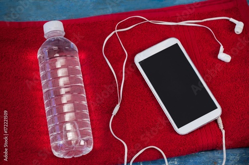 High angle view of water bottle and mobile phone with in-ear