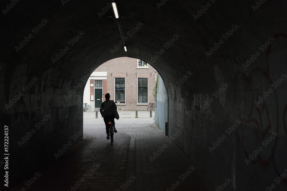 Silhouette of woman cycling in urban tunnel.