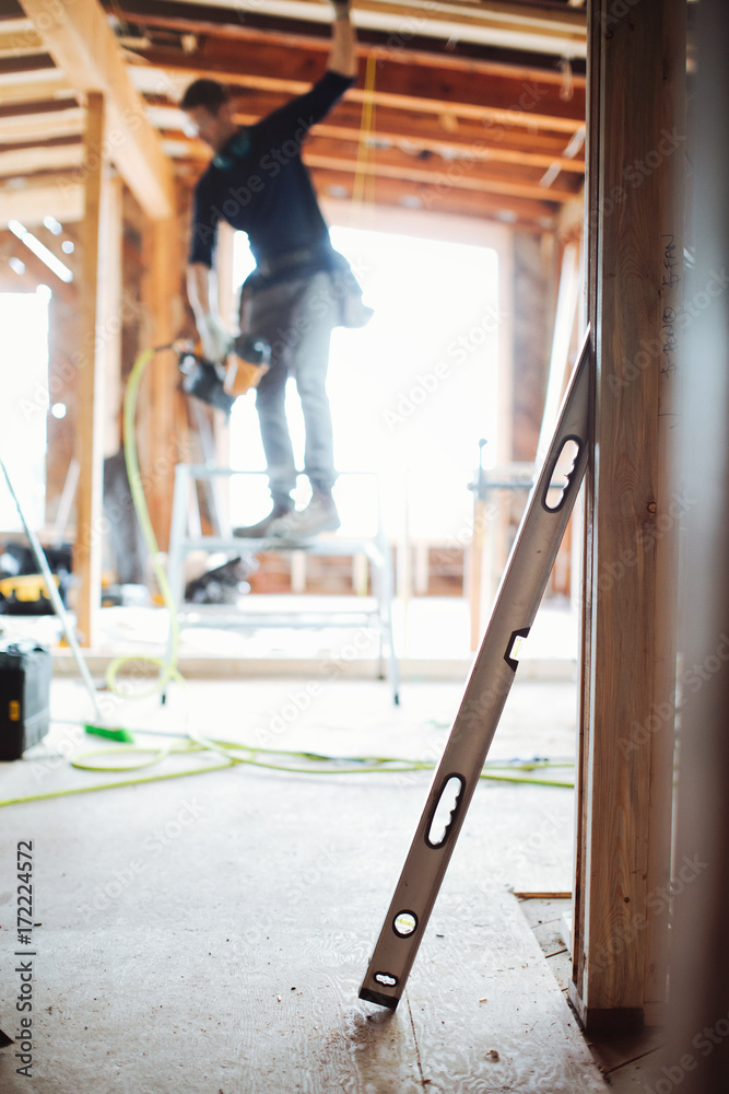 Detail of level with blurry carpenter in background Detail of level with blurry carpenter in background