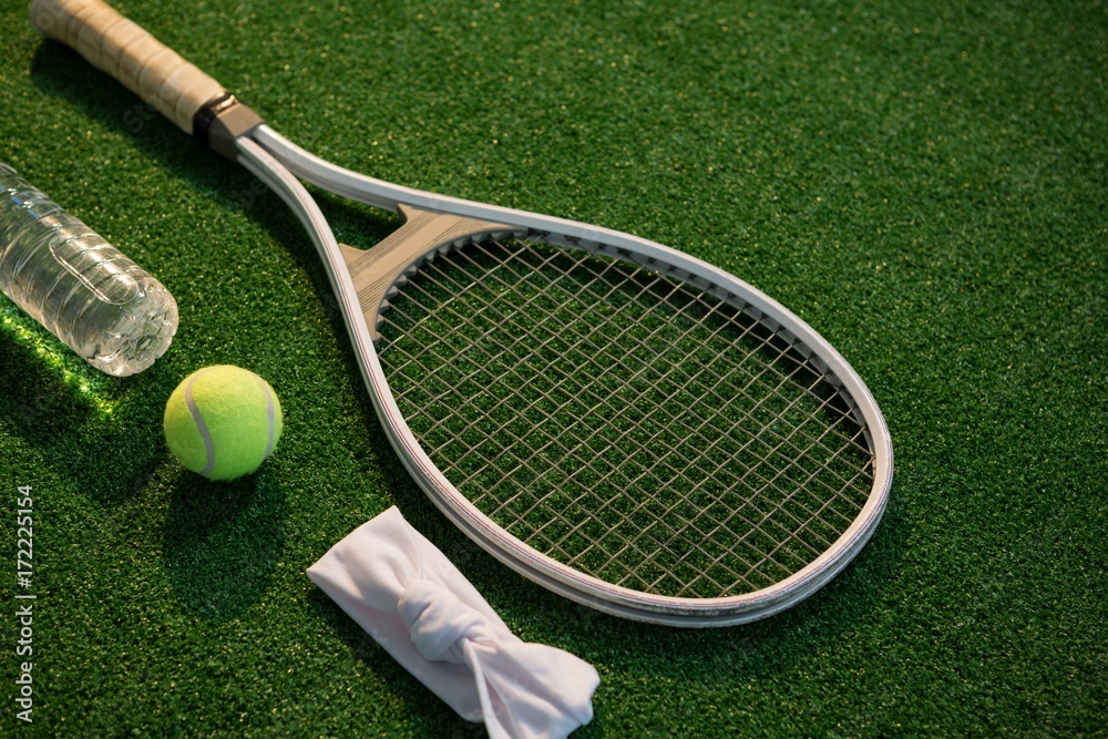 High angle view of tennis ball with racket and napkin by water