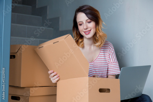 young redhead woman with moving boxes and laptop © Masson