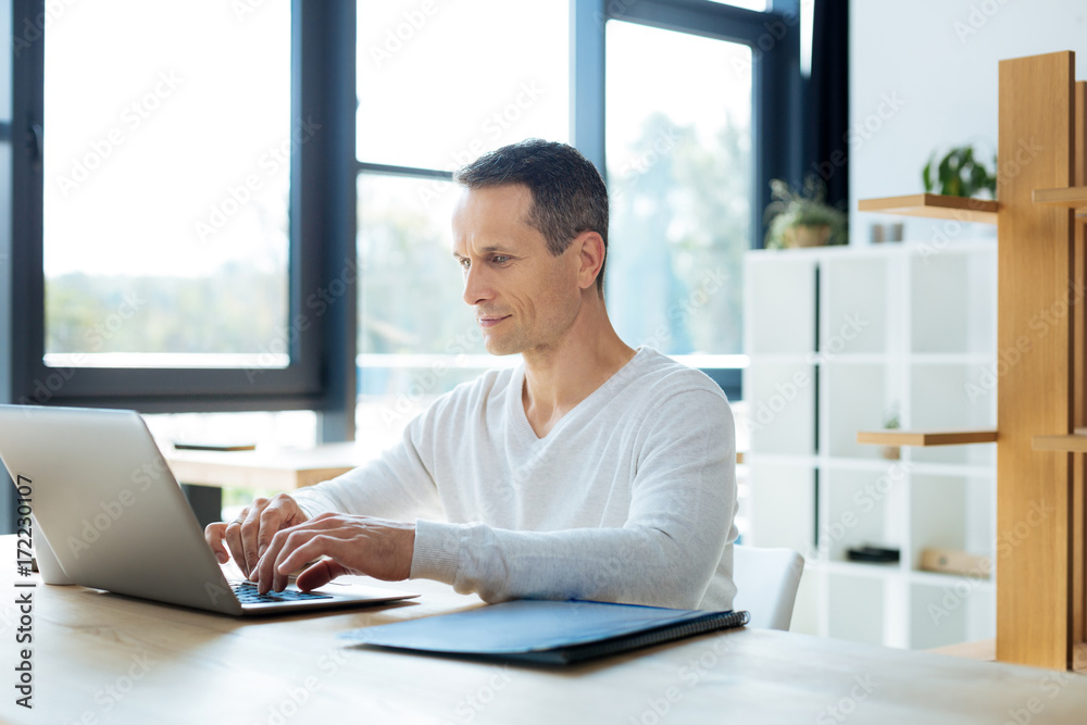 Handsome cheerful businessman typing on the keyboard Handsome cheerful businessman typing on the keyboard