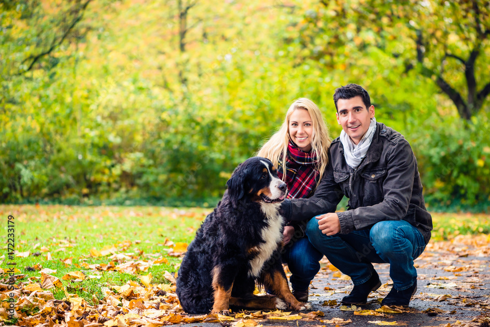 Couple with dog enjoying autumn in nature playing with the pet Couple with dog enjoying autumn in nature playing with the pet