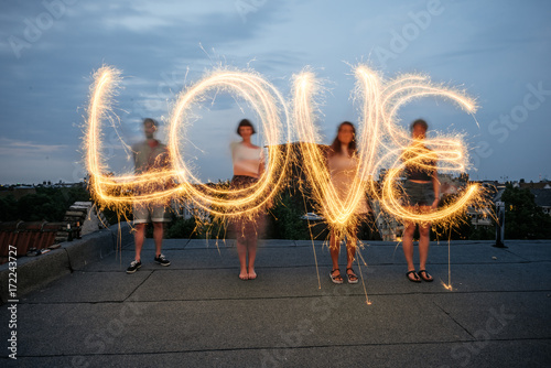 Four people writing the word 'love' with sparklers.