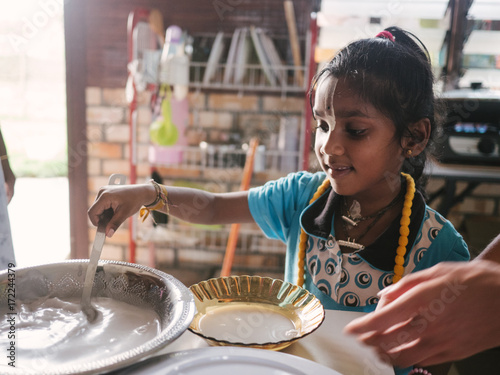 Happy indian girl helping in kitchen photo