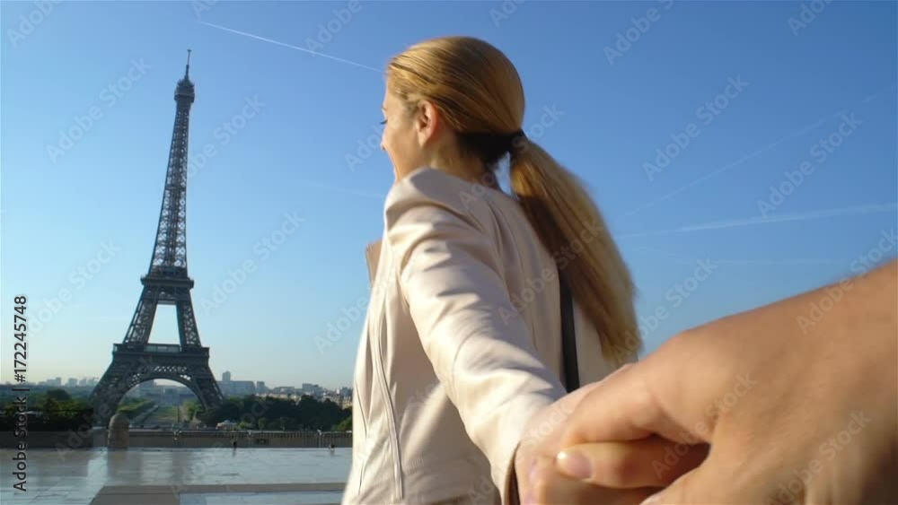 Follow me Paris. Young happy woman leading her boyfriend walking to Eiffel Tower.