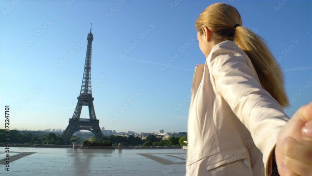 Follow me Paris. Young happy woman leading her boyfriend walking to Eiffel Tower.
