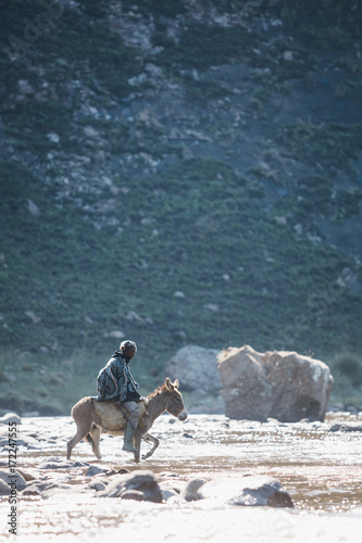 Basotho muleteer crossing a mountain river on a donkey photo