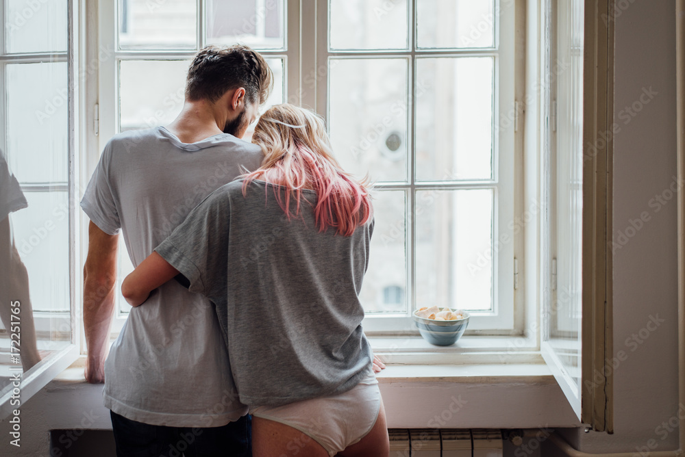 Beautiful Couple Hugging While Standing in Front of the Window