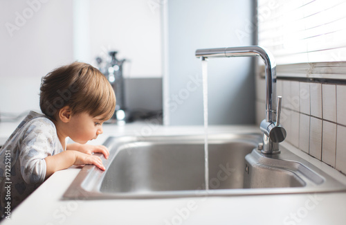 1 year old boy looking into a sink photo