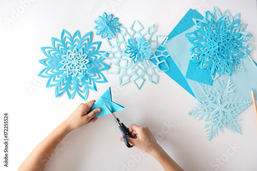 The child does snowflakes of blue paper.