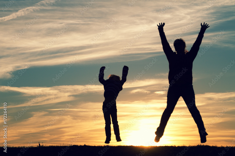 Fototapeta premium a mother and her child jumping at sunset