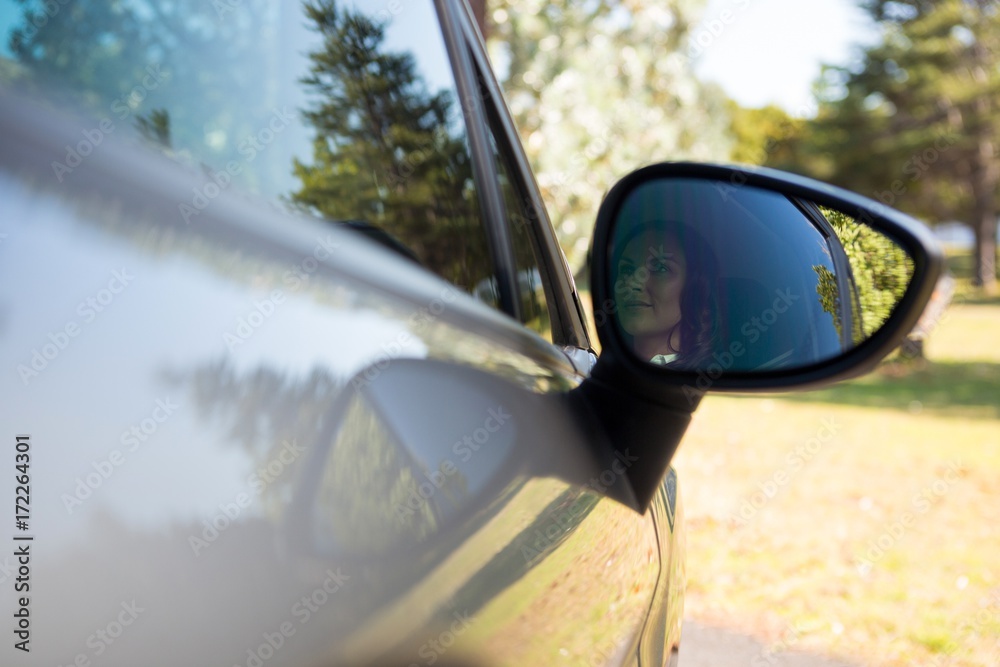 Reflection of woman in wing mirror driving a car