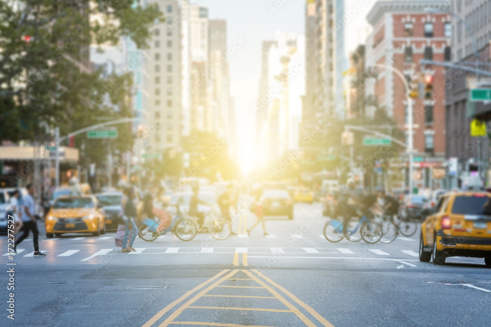 Naklejka premium Ludzie przekraczający ruchliwe skrzyżowanie między ruchem na 3rd Avenue i 10th Street na Manhattanie w Nowym Jorku z blaskiem słońca w tle