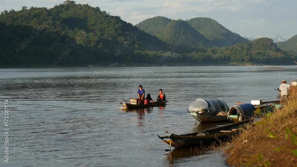 Local people leaving with a long-tail boat at the mekong river in Luang Prabang, Laos Local people leaving with a long-tail boat at the mekong river in Luang Prabang, Laos