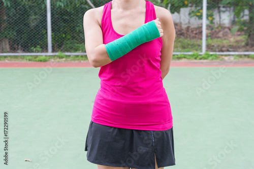 injury woman wearing sportswear  painful arm  with gauze bandage and arm cast standing on tennis court © ttanothai