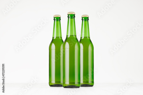 Group green longneck beer bottles 500ml, mock up. Template for advertising, design, branding identity on white wood table.