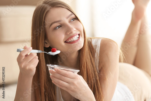 Young woman eating yogurt a...