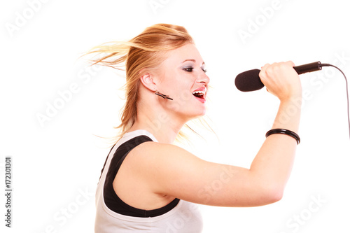 Blonde woman singing to microphone, profile view