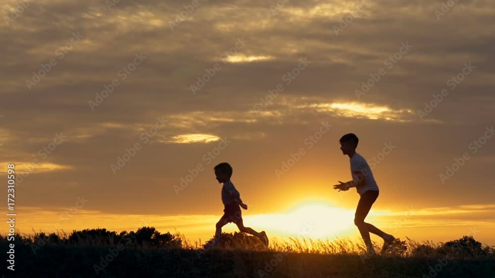 Silhouettes of running children in a field at sunset Silhouettes of running children in a field at sunset