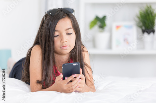 Happy asian girl reading smart phone with smile face on bed .
