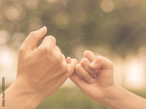 Retro mother holding a hand of her kid in spring day outdoors with green field background