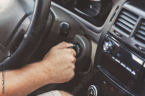 man's hand starts a car with the key in retro toning