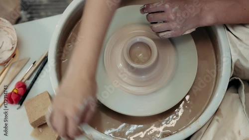 A woman potter makes a clay pot along with her student. Top viem. photo