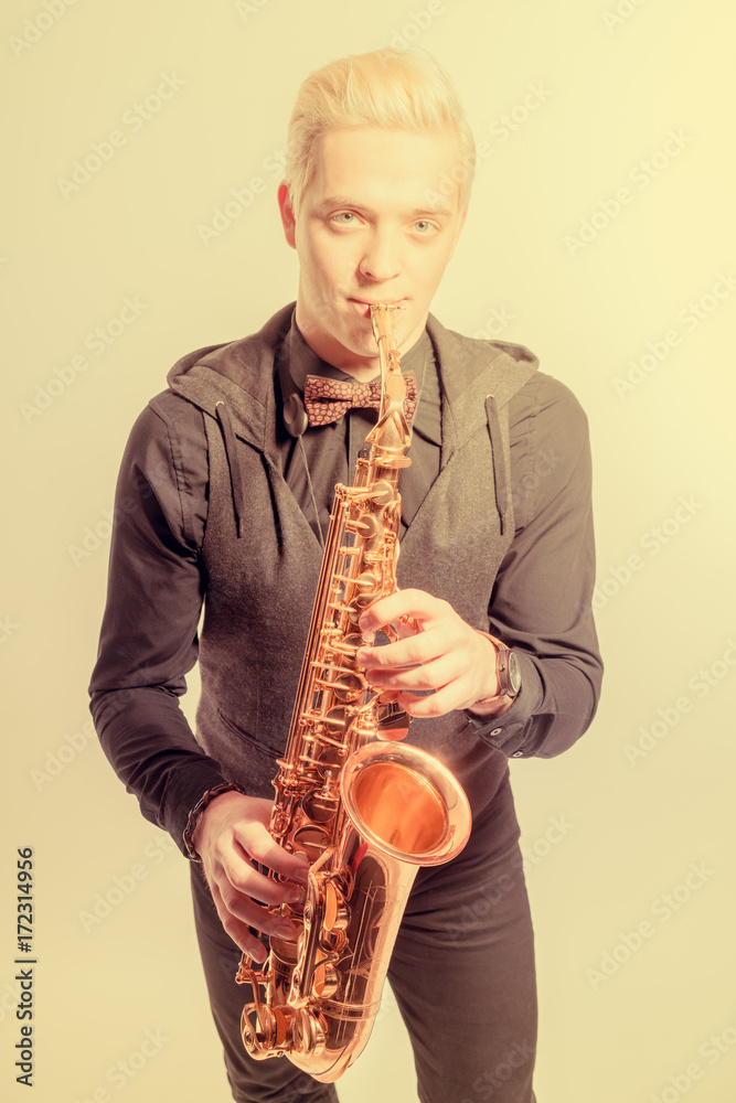 Naklejka premium Elegant blond man dressed in black, playing the saxophone. Toned