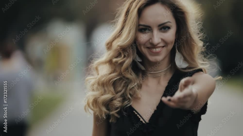 Beautiful woman make come to me gesture walking in city alley, slowmotion