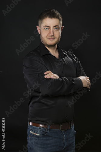 Young confident man portrait of a businessman showing by hands on a black background. Ideal for banners, registration forms, presentation, landings, presenting concept.