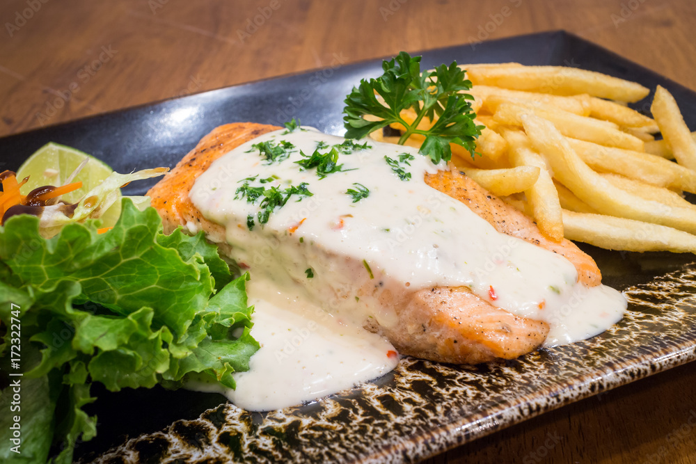 Healthy Grilled Salmon steak, Tartare Cream with salad in a black dish on wood table background for ready to serve. Healthy Grilled Salmon steak, Tartare Cream with salad in a black dish on wood table background for ready to serve.