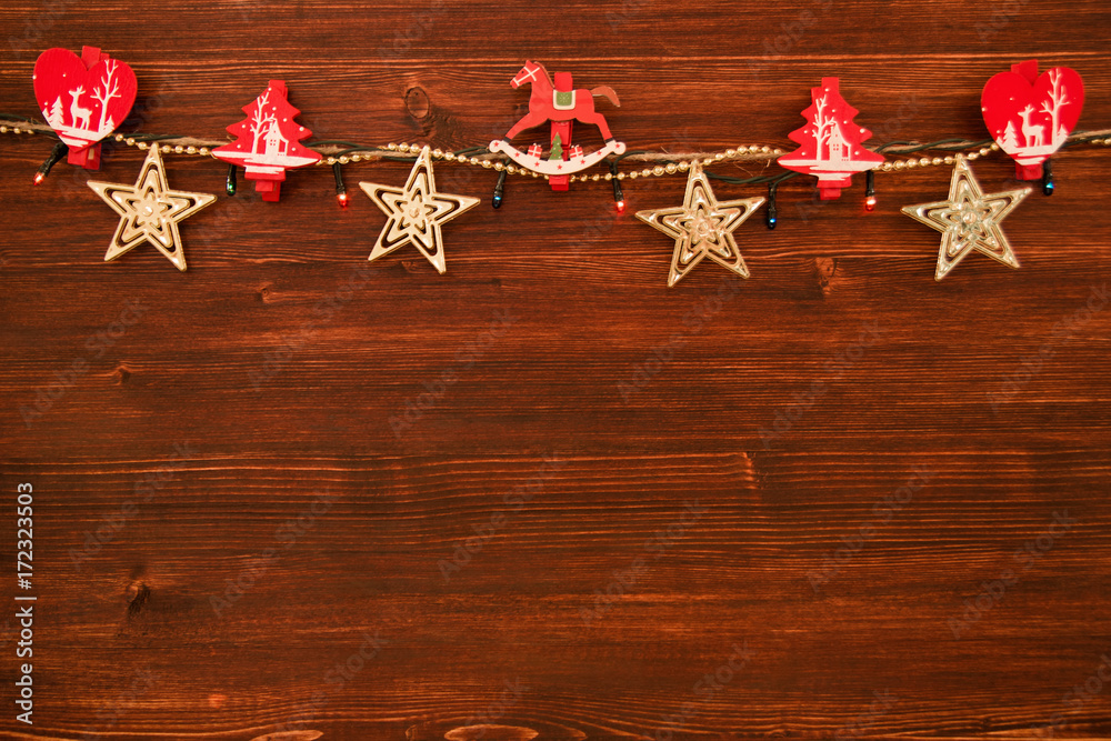 Red and white wooden Christmas decorations and Christmas lights on the brown wooden background, top view. Red and white wooden Christmas decorations and Christmas lights on the brown wooden background, top view.