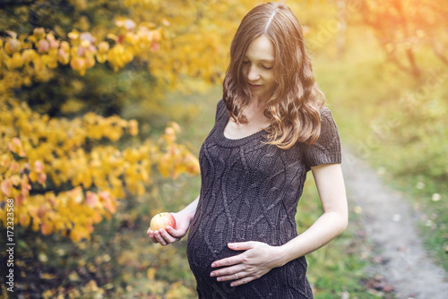 Portrait of pregnant woman belly in colorful autumn forest in September. Concept of pregnancy and the seasons