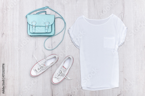 White top, white sneakers and a mint bag. Fashionable concept. Wooden background