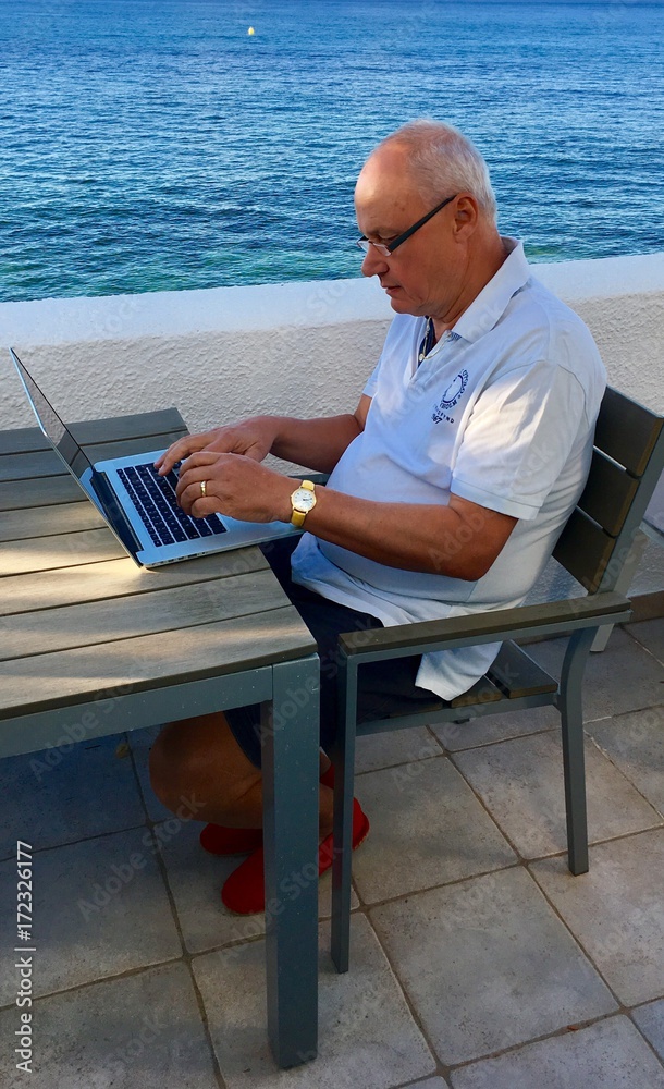 Mann mit Laptop am Meer