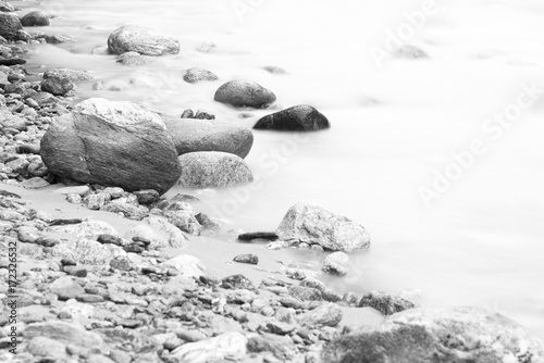 Photography Smooth flowing river with stones on the side in black and white