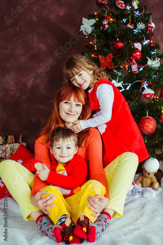 Mother sits with her children before a Christmas tree