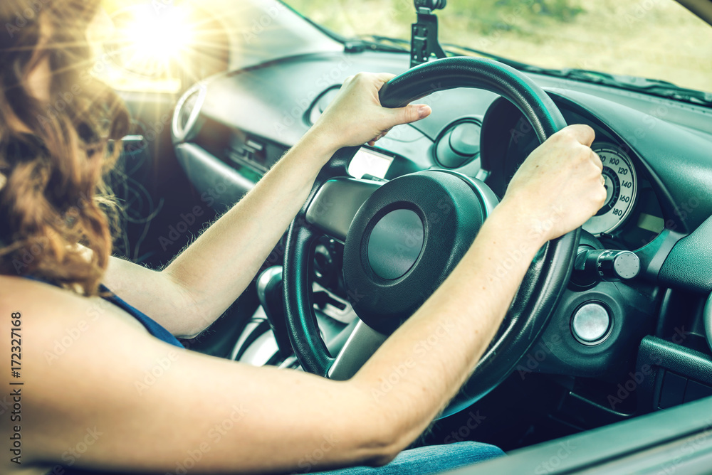 Naklejka premium Closeup of female hands on the steering wheel in the car. Concept travel and road mood