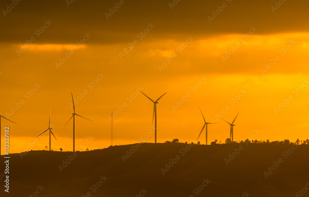 Wind turbines for electricity on a mountain at sunset.