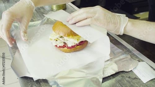Hands wrapping a finished burger in paper and foil