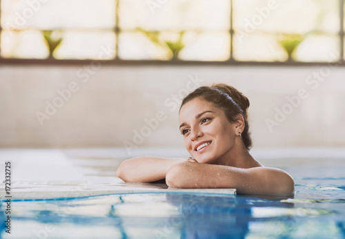Young woman enjoying summer holiday in swimming pool at resort hotel. Spa, retreat, relaxation concept. Beauty and body care