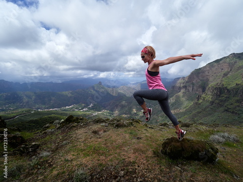 young happy woman jumping on top of the mountain