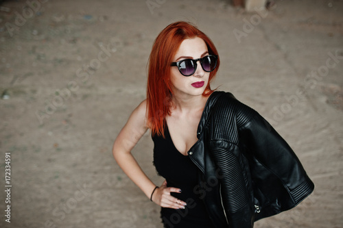 Red haired stylish girl in sunglasses wear in black, against abadoned place. © AS Photo Family