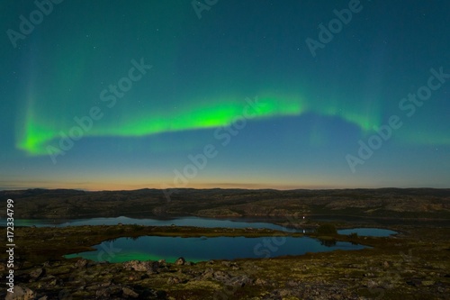 Autumn Aurora over the hills and reflected in the lake. © Moroshka